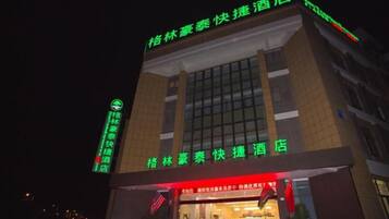 A hotel with a prominent sign indicating it is a 'Quick Hotel' and has a green neon sign on the left side.