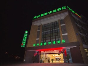 A hotel with a prominent sign indicating it is a 'Quick Hotel' and has a green neon sign on the left side.