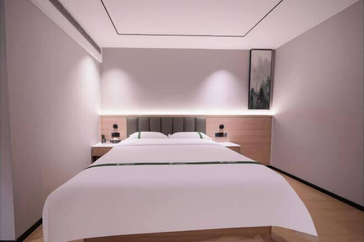 Ein modernes Hotelzimmer mit einem großen Bett, Nachttischen, einem Kopfteil und einem an der Wand befestigten Kunstwerk.
