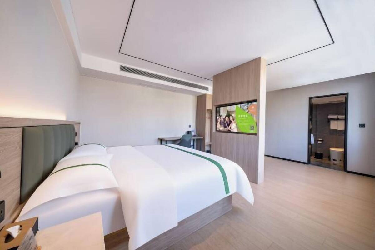Ein modernes Hotelzimmer mit Bett, Schreibtisch, Fernseher und Bad.