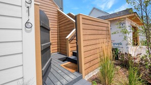 A modern house with a wooden exterior, a visible number '316', and a small outdoor area with steps leading to a door. - Rooftop Retreat (Ottawa)