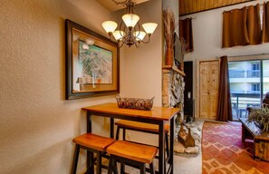 Cozy space with a rustic charm, featuring a wooden table, decorative basket, and stone fireplace.