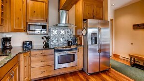 Eine Küche mit Holzschränken, einem Edelstahlkühlschrank, einer Mikrowelle, einem Backofen und einem Gasherd.