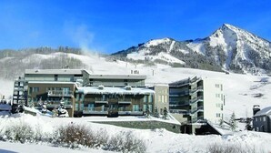 Ein mehrstöckiges Hotel mit Balkonen, gelegen in einer verschneiten Berglandschaft.
