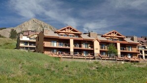 A multi-story lodge with a mountain backdrop, featuring balconies and a stone facade. - Rustic Mountain Retreat with Stunning Views (Crested Butte)