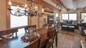 A spacious living area with a wooden dining table, a chandelier, and a fireplace. - Spacious 2BR Condo | Stunning Mountain Views (Crested Butte)