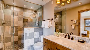 Une salle de bain moderne avec une douche à parois de verre, un lavabo en marbre et des meubles en bois.
