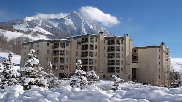 Un hôtel à plusieurs étages, avec un paysage enneigé et des montagnes en arrière-plan.