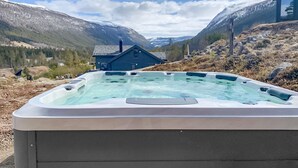 Un jacuzzi en una zona montañosa, con una casa al fondo.
