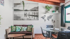 Un saló modern amb sostre de fusta, un sofà amb coixins estampats, una taula de dinar de vidre i una obra d'art mural d'un mapa del món.