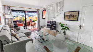 Una sala de estar moderna con un sofá, una mesa de centro de vidrio y un televisor.