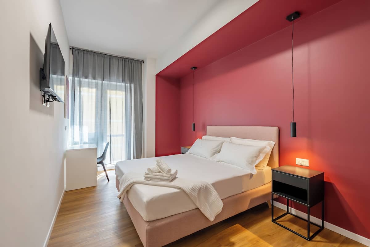 A modern bedroom with a bed, bedside table, and a TV mounted on the wall.