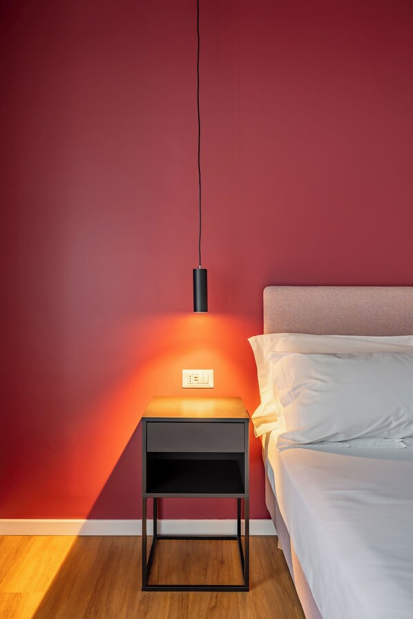Une chambre à coucher avec un lit, une table de chevet et une lampe fixée au mur.