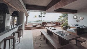A modern interior with a kitchen, dining area, and seating overlooking a pool. - Luxury and Serenity by the Sea by BT Homes (Tulum)
