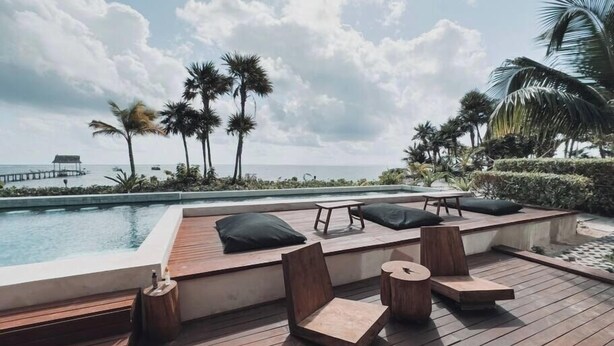 A wooden deck with lounge chairs and a pool overlooking the ocean. - Luxury and Serenity by the Sea by BT Homes (Tulum)
