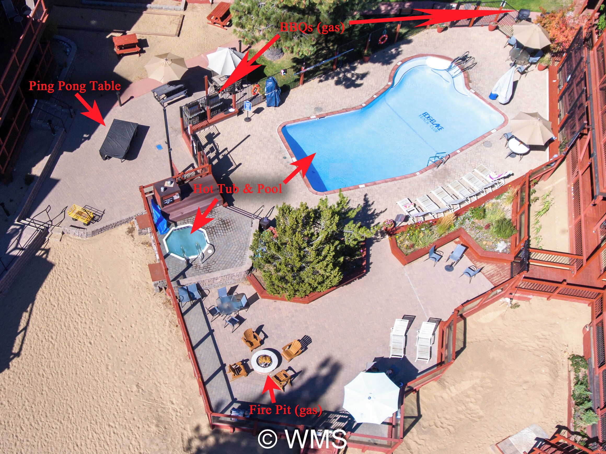 Vista aérea de um resort com piscina, mesa de tênis de mesa, banheira de hidromassagem e lareira.