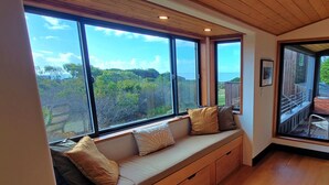 A room with a built-in bench along a large window overlooking a garden and a body of water. -  NEW 3BR/3Bath Ocean Views 2-min walk to Bluff Trail Close to Town (Sea Ranch)