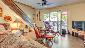 A cozy living room with a large TV, comfortable seating, a ceiling fan, and a view to the outdoors. - Blue Ridge Lake Townhome ~ 7 Mi to Scenic Railway! (Morganton)