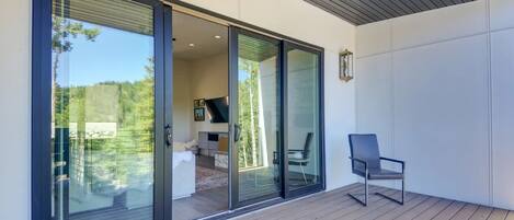 A modern outdoor area with a wooden deck, a glass door leading to an interior space, and a chair.