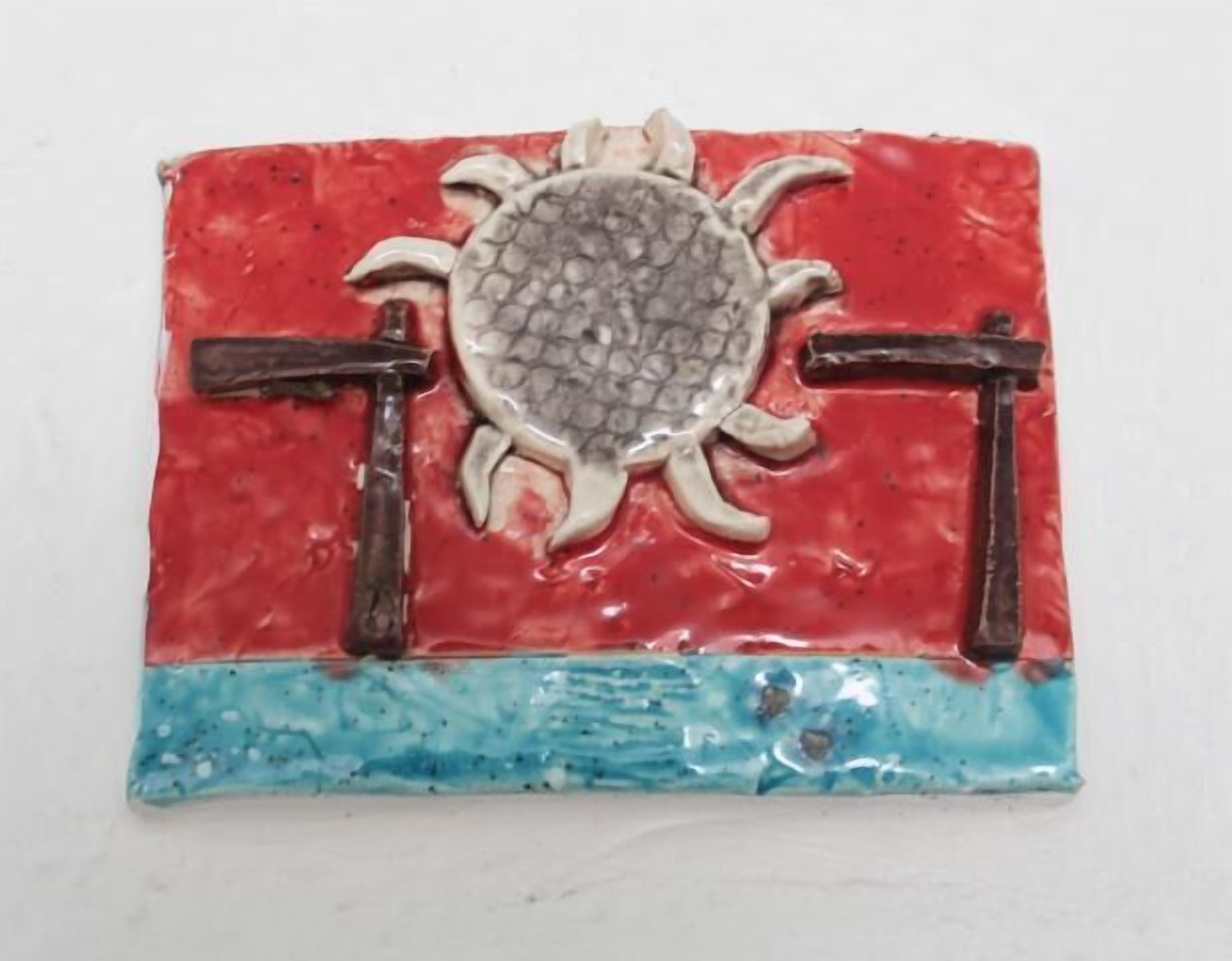 A ceramic tile with a sun and two crosses.
