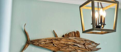 A wall with a wooden fish decoration and a hanging light fixture.