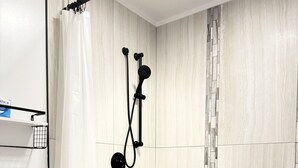 Un bagno moderno con doccia, servizi igienici e pavimento piastrellato.