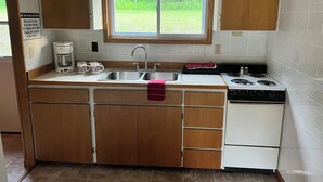 Una cocina compacta con un lavamanos, estufa y armarios.