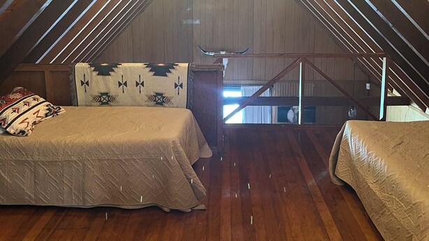 Ein Schlafzimmer im Dachgeschoss mit zwei Betten, Holzboden und Lichterkette.