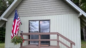 Ein kleines Holzgebäude mit Veranda, einer Flagge und einem Fenster.