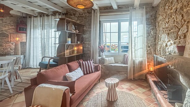 Un salon chaleureux avec un canapé, une table basse, une cheminée et un mur en pierre.