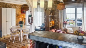 Une cuisine chaleureuse avec un mur en pierre, des meubles blancs, une table de salle à manger ronde et des luminaires suspendus.