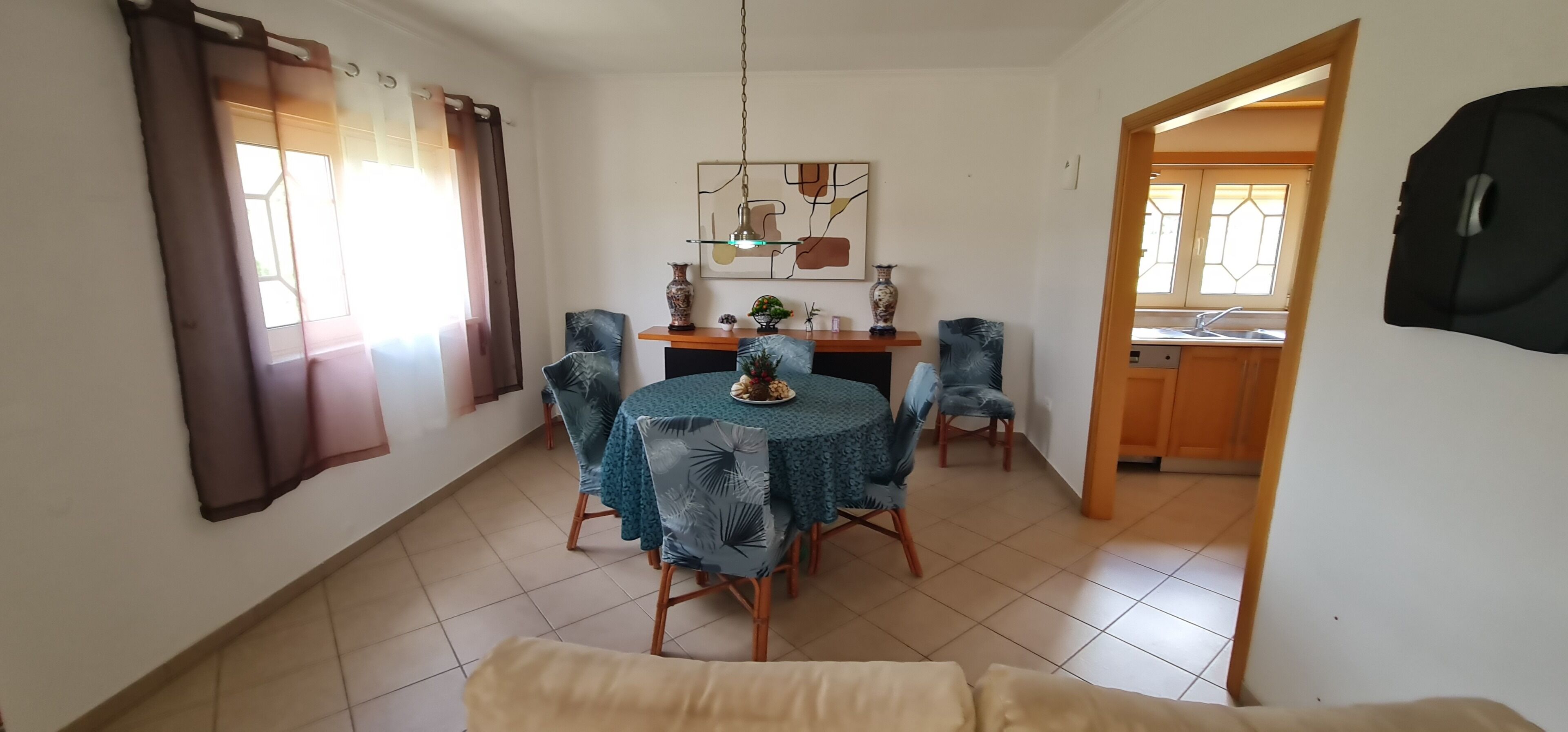 A dining area with a round table, chairs, and a vase on a shelf.