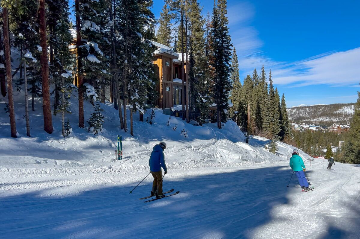 A ski resort with a lodge surrounded by tall pine trees and a snowy landscape.