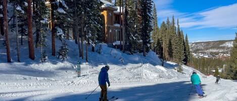 A ski resort with a lodge surrounded by tall pine trees and a snowy landscape.