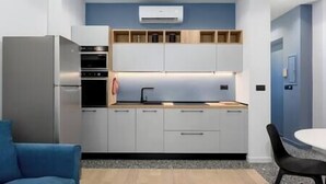 A modern kitchen with built-in appliances, wooden shelves, and a blue accent wall. - [Center - Metro] Stylish and Modern Two-room apartment (Turin)