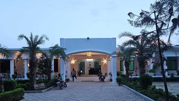 A hotel entrance with a paved walkway, palm trees, and a 'No Parking' sign. - Tiger Tales Resort (Palia Kalan)