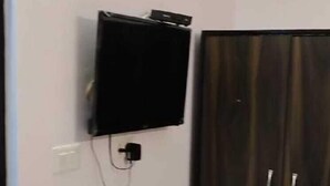 A room with a dark wooden wardrobe, a wall-mounted television, and a power outlet. - Tiger Tales Resort (Palia Kalan)