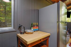 A kitchen with a wooden table, a refrigerator, and bottles of alcohol.