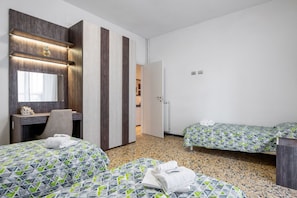 Une chambre d’hôtel équipée d’un lit, d’un bureau, d’une chaise, d’un miroir et d’une armoire.