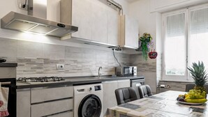 A modern kitchen with a built-in washing machine, a microwave, and a dining area with a table set for two. - GuestHost - Nice apartment of 68 square meters, ideal for 5 people, located on the second floor of a building with a lift (5/6 steps to access it). Located in a central position and a 7-minute walk from La Spezia Centrale train station.The apartment is i (La Spezia)