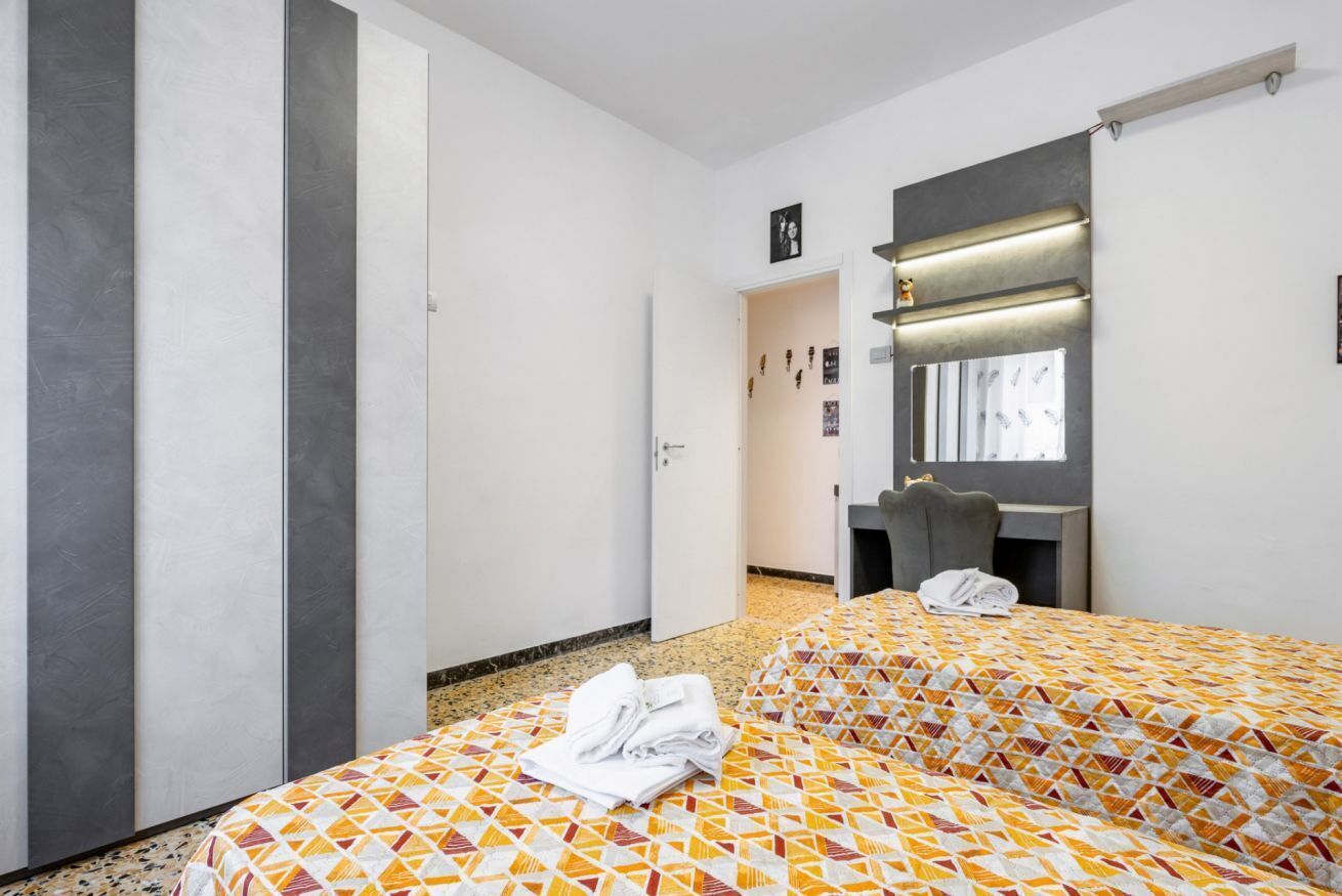 A hotel room with a bed, a desk, a chair, and a wardrobe.