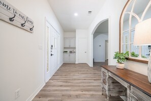 A hallway with wooden flooring, white walls, and a sign that reads "home to our home".
