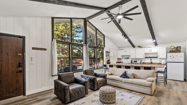Amplia sala de estar con techo alto, ventanas grandes y una zona de cocina.
