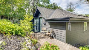 A modern house with a wooden deck, a glass door, and a small outdoor seating area. - Pet-Friendly Minneapolis Studio: Walk to Lake! (Minneapolis)
