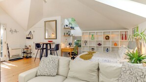 A spacious loft bedroom with a large bed, a sitting area with a sofa and chairs, a desk, and a skylight. - Pet-Friendly Minneapolis Studio: Walk to Lake! (Minneapolis)