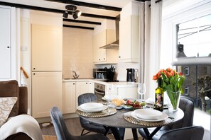A modern kitchen with white cabinets, a dining table set for four, and a vase of tulips on the table. - Northern Hideaways, Castle View (Bellingham)