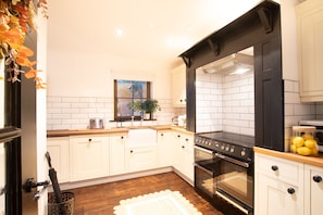 A kitchen with white cabinets, a black stove, and a window with a plant.