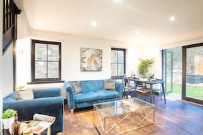 Un salon moderne avec un canapé bleu, une table basse en verre et un coin repas comprenant une table et des chaises.