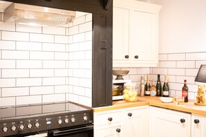 A kitchen with white cabinets, a black stove, and a wooden countertop. - Northern Hideaways, Apple Store, Ellingham (Chathill)