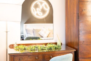 A bathroom vanity with a mirror, a green plant, and a bottle of reed diffuser.